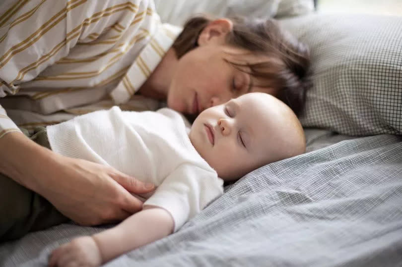 A mother taking his 6 month old baby boy in her arms at home - nap time