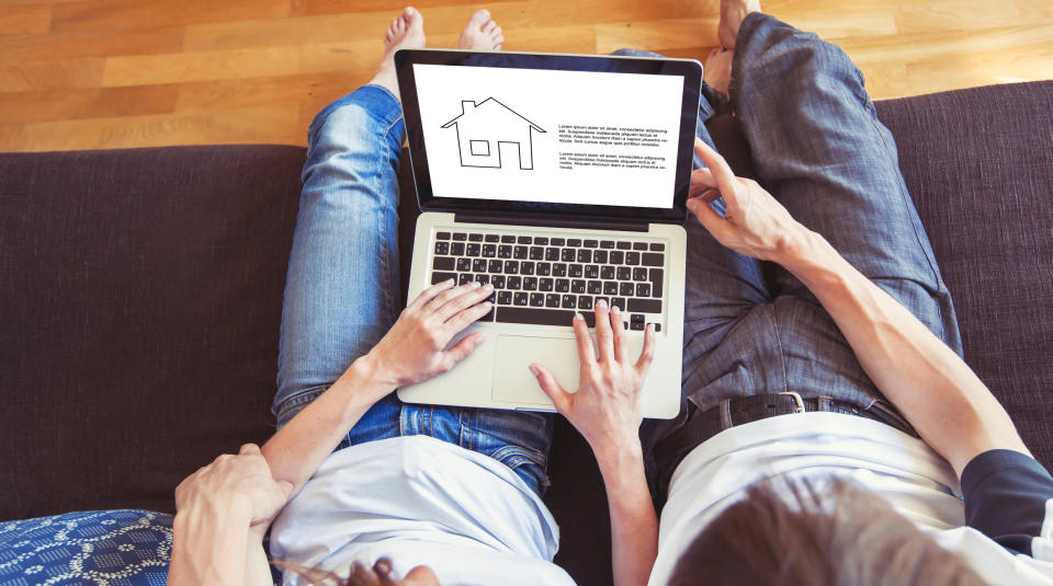 Couple win laptop on their lap looking at a house outline