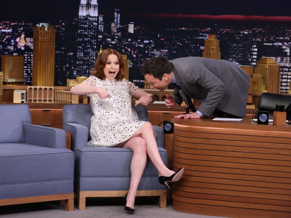 Ellie Kemper pointing to her baby bump on the set of Jimmy Fallon's show.