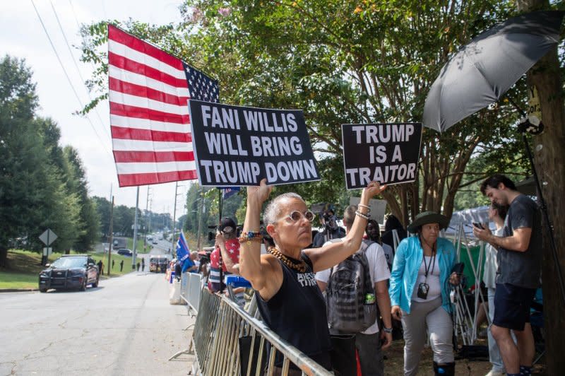 Protester Laurie Arbeiter holds signs outside the Fulton County Jail in Atlanta on Thursday ahead of former President Donald Trump's surrender on election interference charges. Photo by Anthony Stalcup/UPI