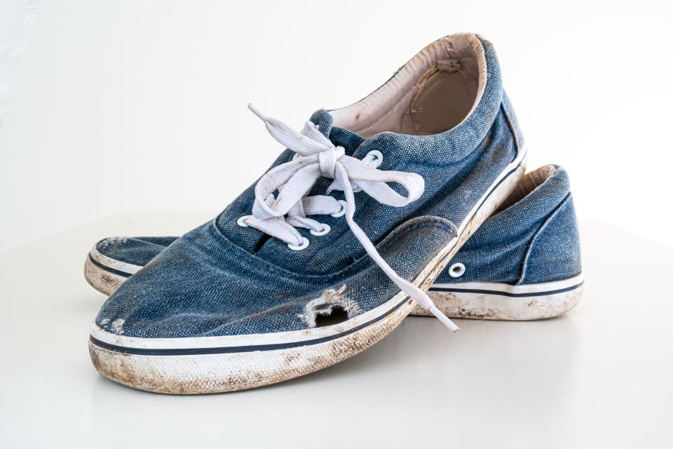 A pair of worn-out kids' sneakers with untied laces