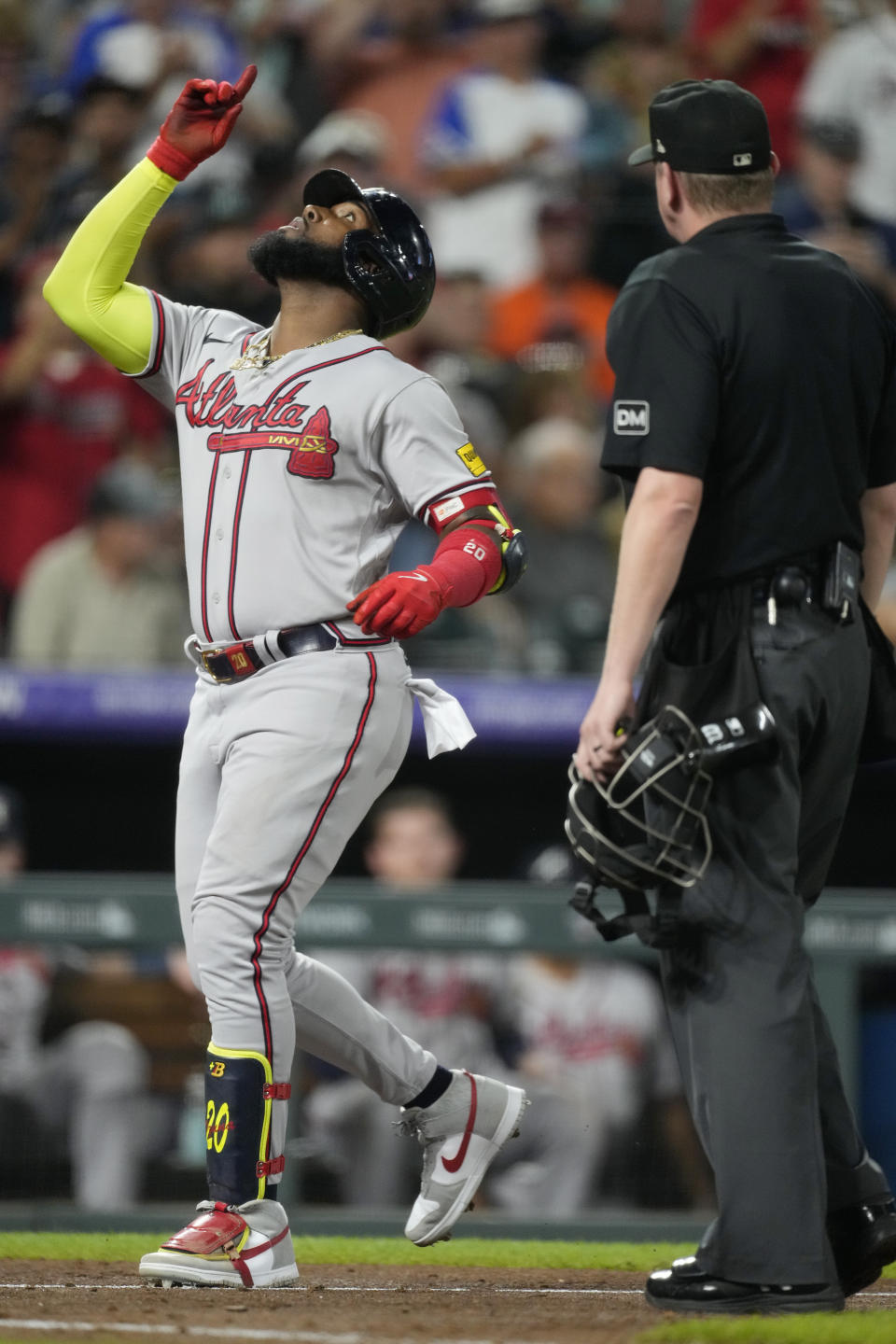 Atlanta Braves' Marcell Ozuna, left, gestures as he crosses home plate as home plate umpire Ryan Wills looks on in the sixth inning of a baseball game against the Colorado Rockies Wednesday, Aug. 30, 2023, in Denver. (AP Photo/David Zalubowski)