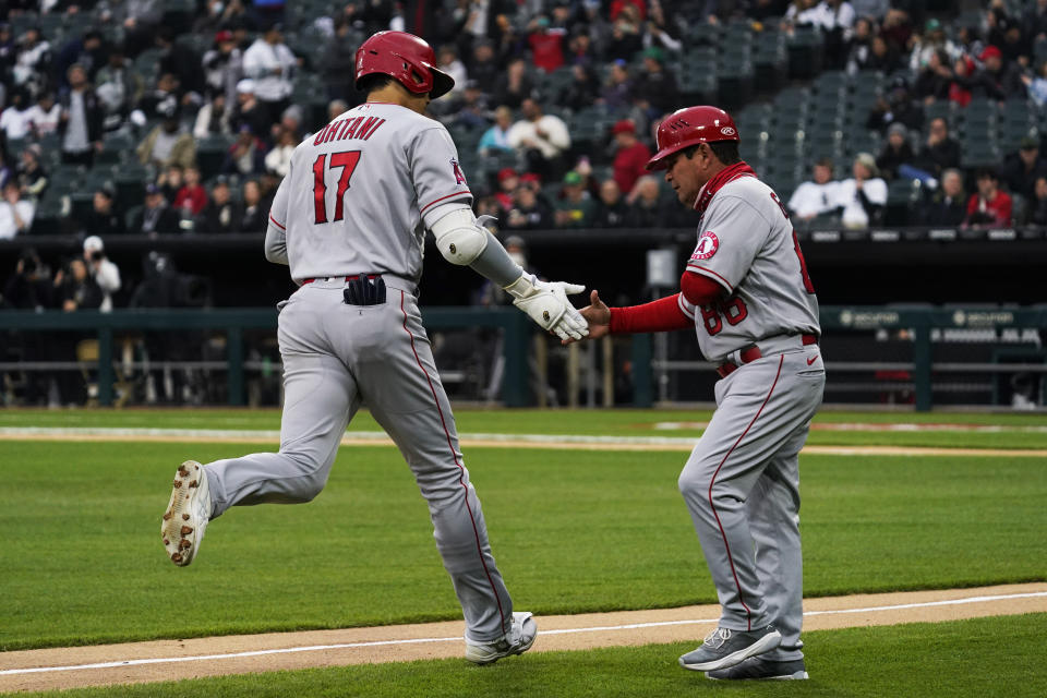 Los Angeles Angels third base coach Phil Nevin, right, congratulates Shohei Ohtani, of Japan, after Ohtani's solo nome run during the first inning of a baseball game against the Chicago White Sox in Chicago, Friday, April 29, 2022. (AP Photo/Nam Y. Huh)