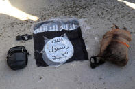 This photo provided by the Kurdish-led Syrian Democratic Forces shows the flag of the Islamic State and and bags taken from fighters who were arrested by the Kurdish-led Syrian Democratic Forces after IS militants attacked Gweiran Prison, in Hassakeh, northeast Syria, Friday, Jan. 21, 2022. Clashes between U.S.-backed Syrian Kurdish fighters and militants continued for a fourth day Sunday near a prison in northeastern Syria that houses thousands of members of the Islamic State group, the Kurdish force said. (Kurdish-led Syrian Democratic Forces, via AP, File)