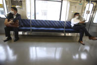 People wearing face masks to protect against the spread of the new coronavirus keep social distancing in a train in Yokohama, near Tokyo, Thursday May 28, 2020. Japanese Prime Minister Shinzo Abe lifted a coronavirus state of emergency on Monday, ending the restrictions nationwide as businesses begin to reopen. (AP Photo/Koji Sasahara)