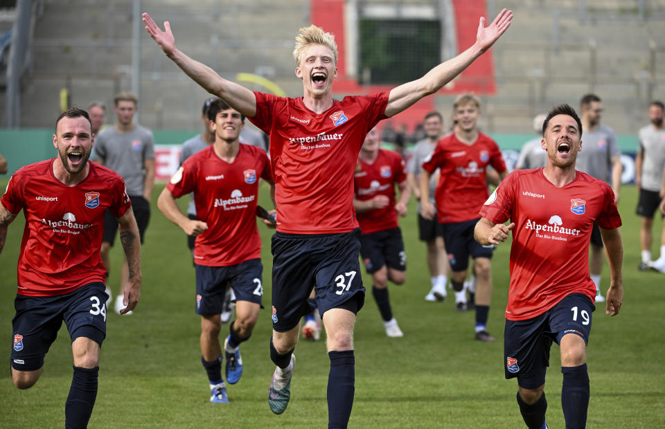 Patrick Hobsch, from left, Raphael Schifferl and Maximilian Welzm'ller of Unterhaching cheer after the match during the German Soccer Cup game between Unterhaching and Augsburg, in Unterhaching, Germany, Sunday Aug. 13, 2023. (Sven Hoppe/dpa via AP)