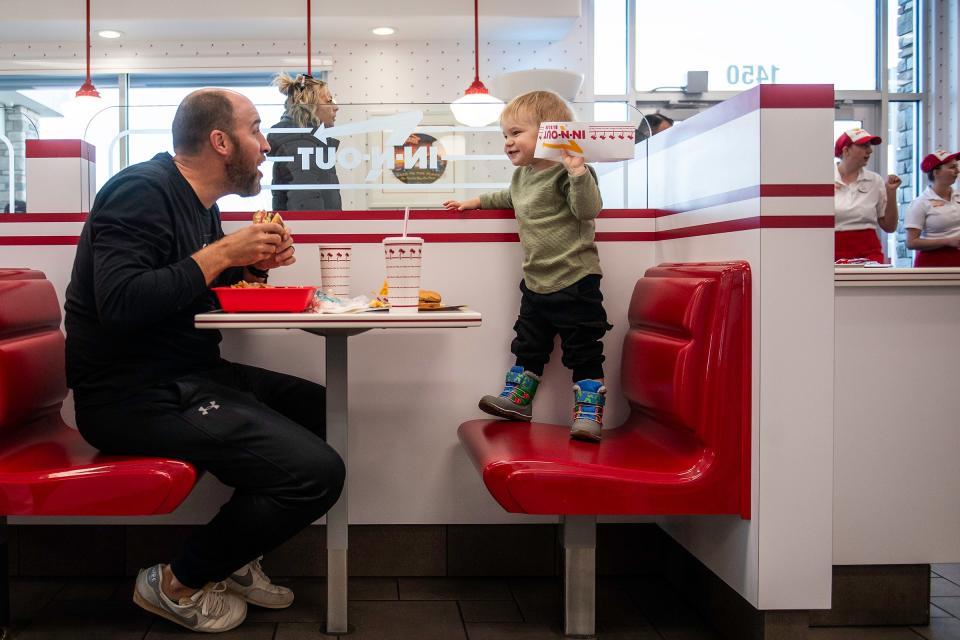 Brandon Pierce, left, interacts with Judah Pierce before taking a bite of his meal during the opening of Colorado's new In-N-Out location in Loveland, Colo., on Friday, Nov. 10, 2023.