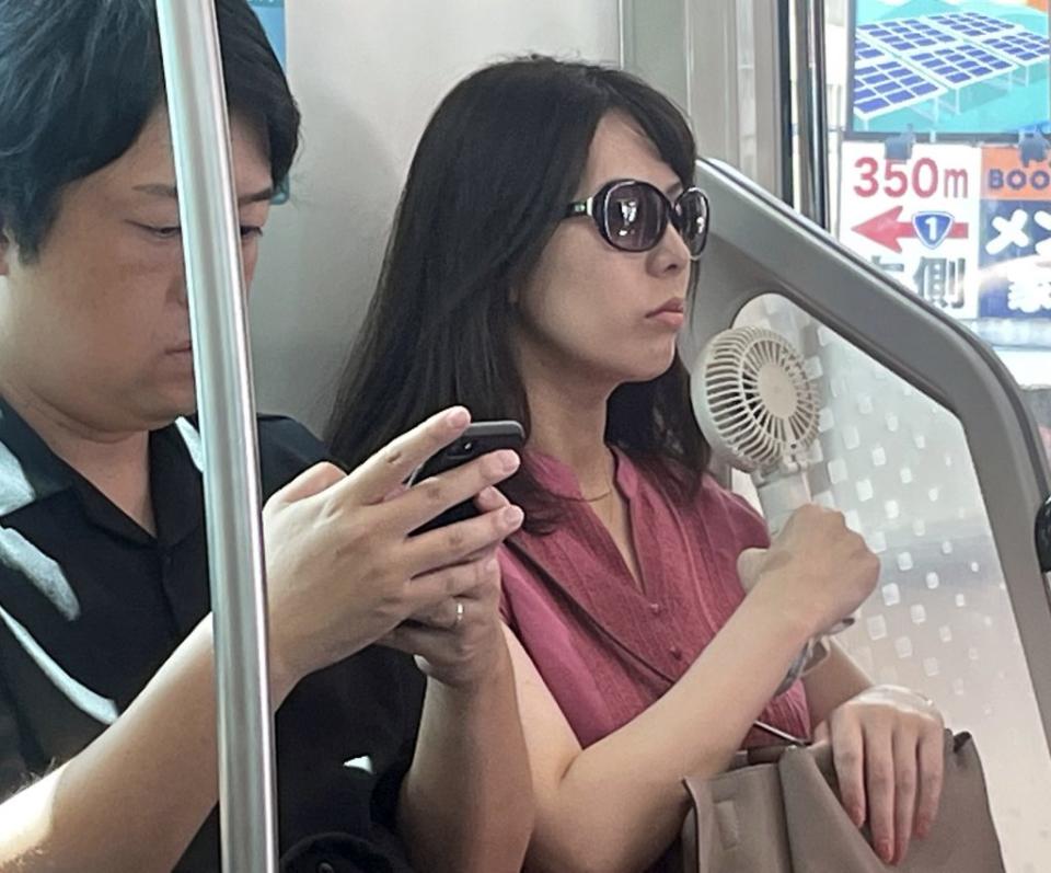 日本女性幾乎人手一支顏面風扇吹臉消暑。（記者陳俊文攝）