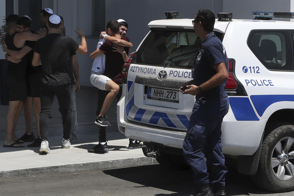 An Israeli teenager is embraced by relatives after being released from Famagusta police headquarters in southeast town of Paralimni, Cyprus, Sunday, July 28, 2019. A lawyer says Cyprus police will release all seven Israeli teenagers who were being detained as suspects in the alleged rape of a 19-year-old British woman. Cypriot Lawyer Yiannis Habaris, who represents two of the seven Israelis, told The Associated Press on Sunday the British woman has been arrested and faces a public nuisance charge. (AP Photo/Petros Karadjias)