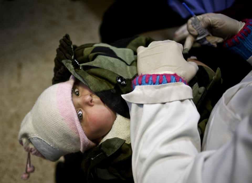 This Wednesday, Dec. 18, 2013 photo shows UNICEF nurse Nadine Houjairi removing the winter coat from a Syrian baby before giving the measles vaccine at the U.N. refugee agency's registration center in Zahleh, in Lebanon's Bekaa Valley. The baby and her siblings were also vaccinated against polio as part of a U.N. campaign to prevent disease among the Syrian refugee population. With an endless surge of refugees now fighting the bitter winter cold, humanitarian organizations are struggling to find new ways to reach refugees with the timely, accurate information they need to survive, including the recruitment of refugees as volunteers so that people can access information from sources they can trust. (AP Photo/Maya Alleruzzo)