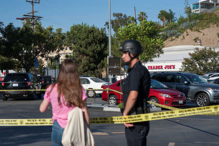 A police officer talks with a woman in a parking lot across the street from a Trader Joe's store where a hostage situation unfolded in Los Angeles, California, Saturday July 21, 2018. REUTERS/Andrew Cullen