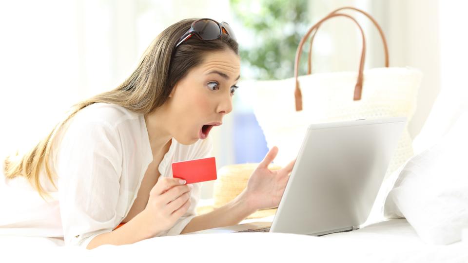 Amazed woman looking surprised at her notebook computer screen, while holding a red card.