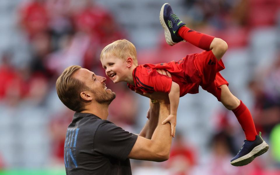 Harry Kane lifts his son Louis up on the pitch