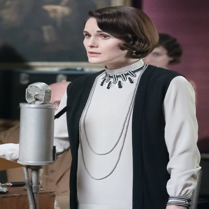 Michelle Dockery as Lady Mary sings into a microphone.