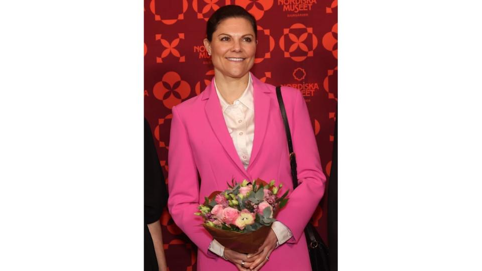 Crown Princess Victoria in a pink suit holding a bouquet of flowers