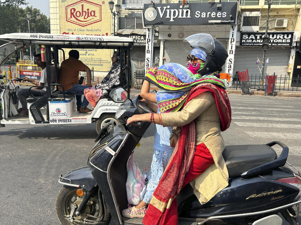 A woman rider covers her daughter's head with a scarf to protect her from severe heat in Lucknow, India, Saturday, May 18, 2024. Swathes of northwest India sweltered under scorching temperatures on Saturday, with the capital New Delhi under a severe weather alert as extreme temperatures strike parts of the country. (AP Photo/Rajesh Kumar Singh)