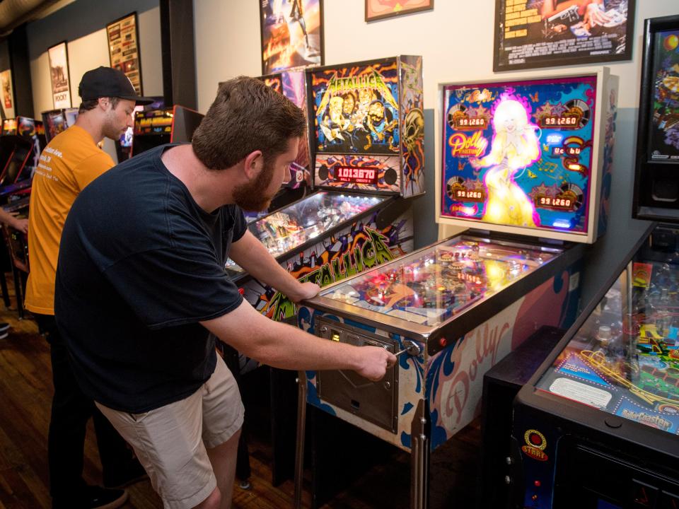 Ryan Wilusz, downtown reporter for Knox News, plays the Dolly Parton pinball machine at Suttree's High Gravity Tavern.
