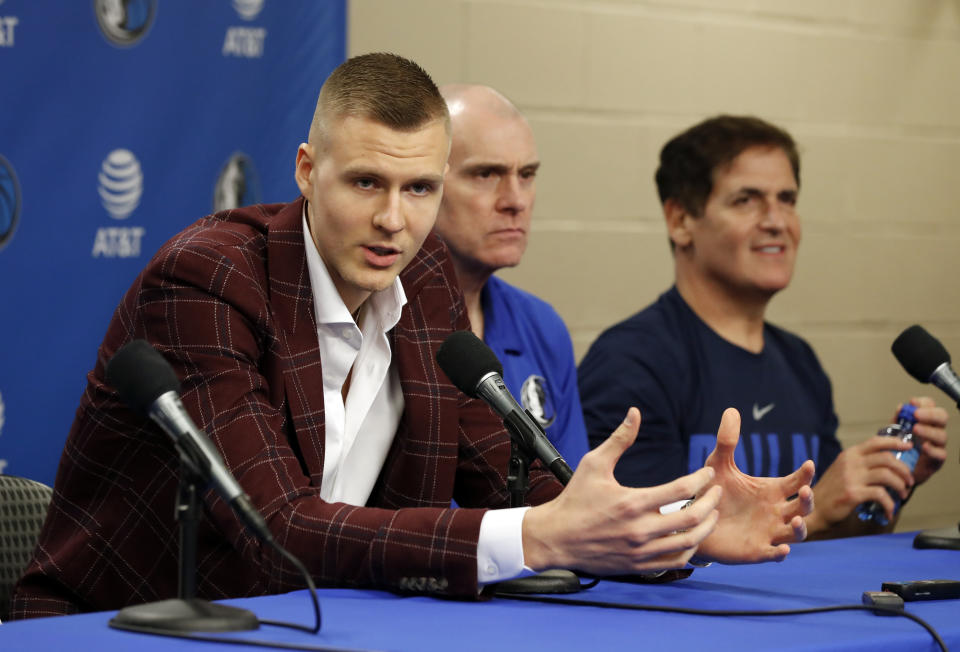 Newly acquired player Kristaps Porzingis, left, responds to questions as head coach Rick Carlisle, center, and team owner Mark Cuban, right, listen during a news conferences where the newly acquired players were introduced in Dallas, Monday, Feb. 4, 2019. (AP Photo/Tony Gutierrez)