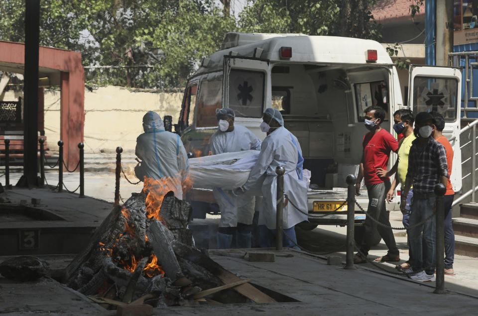 Health workers carry a body of a person who died of COVID-19 for cremation, in New Delhi, India, Monday, April 19, 2021. New Delhi imposed a weeklong lockdown Monday night to prevent the collapse of the Indian capital's health system, which authorities said had been pushed to its limit amid an explosive surge in coronavirus cases. (AP Photo/Manish Swarup)