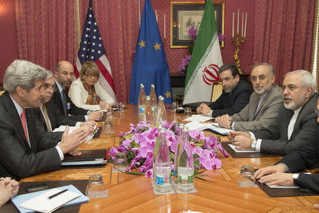 U.S. Secretary of State John Kerry (L) expresses his condolences over the death the of the mother of Iranian President Hassan Rouhani before a negotiation session with Iran's Foreign Minister Javad Zarif (R) over Iran's nuclear program in Lausanne March 20, 2015. Also at the negotiating table is European Union Political Director Helga Schmid (rear C). REUTERS/Brian Snyder