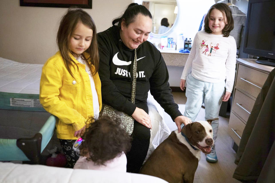 Chloe Kelly, 7, left, Shantel Kelly, 1, mother Janet Kelly, 40, and Zoey Kelly, 9, play with their family dog named Blue (Sarahbeth Maney / Detroit Free Press via Zuma Press)