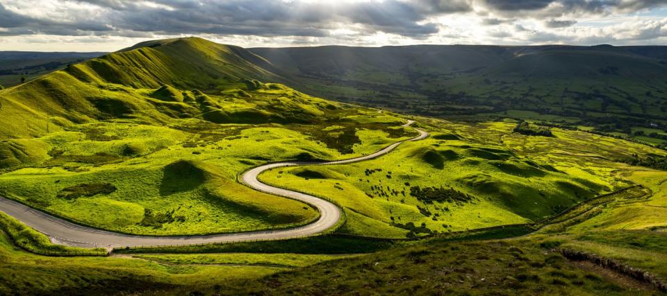 visit peak district road winding through green hills