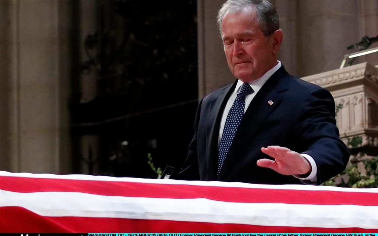 George W Bush touches the casket of his father George H W Bush during a funeral ceremony - Getty Images North America