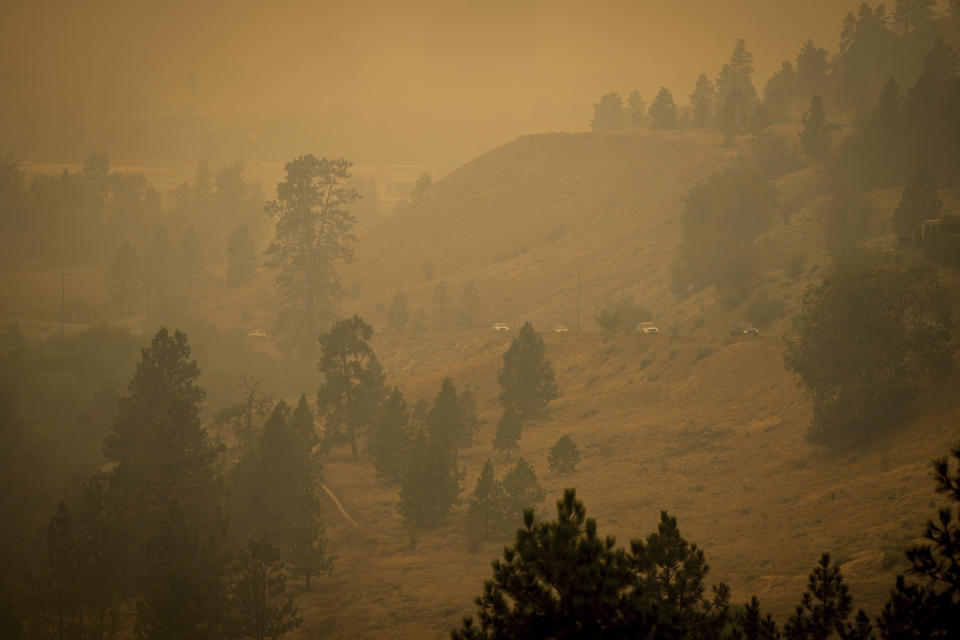 Smoke from wildfires fills the air as motorists travel on a road on the side of a mountain, in Kelowna, British Columbia, Saturday, Aug. 19, 2023. (Darryl Dyck/The Canadian Press via AP)