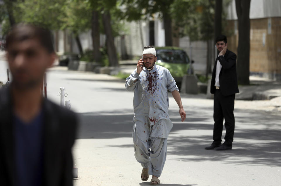 An Afghan injured man walks as he talks with his mobile cell phone after a huge explosion in Kabul, Afghanistan, Wednesday, May 8, 2019. Insurgents targeted the counterpart international organization located near the offices of the attorney general in the capital Kabul, said Afghan officials on Wednesday. (AP Photo/Rahmat Gul)