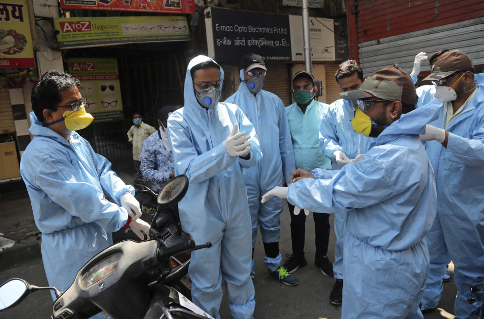 Members of a voluntary organization wear protective gear before distributing food to people in Mumbai, India, Sunday, March 29, 2020. Indian Prime Minister Narendra Modi apologized to the public on Sunday for imposing a three-week national lockdown, calling it harsh but "needed to win" the battle against the coronavirus pandemic. The new coronavirus causes mild or moderate symptoms for most people, but for some, especially older adults and people with existing health problems, it can cause more severe illness or death. (AP Photo/Rafiq Maqbool)