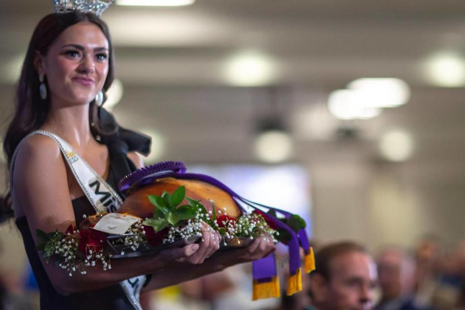 Miss Kentucky Mallory Hudson holds the ham offered for auction at the 59th Annual Country Ham Breakfast at the Kentucky Exposition Center in Louisville, Ky., on Thursday, Aug. 24, 2023.