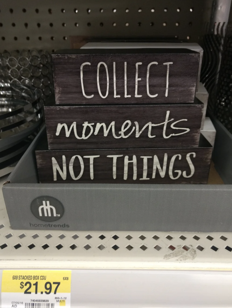 Decorative sign on a shelf stating "COLLECT moments NOT THINGS" with a price tag below