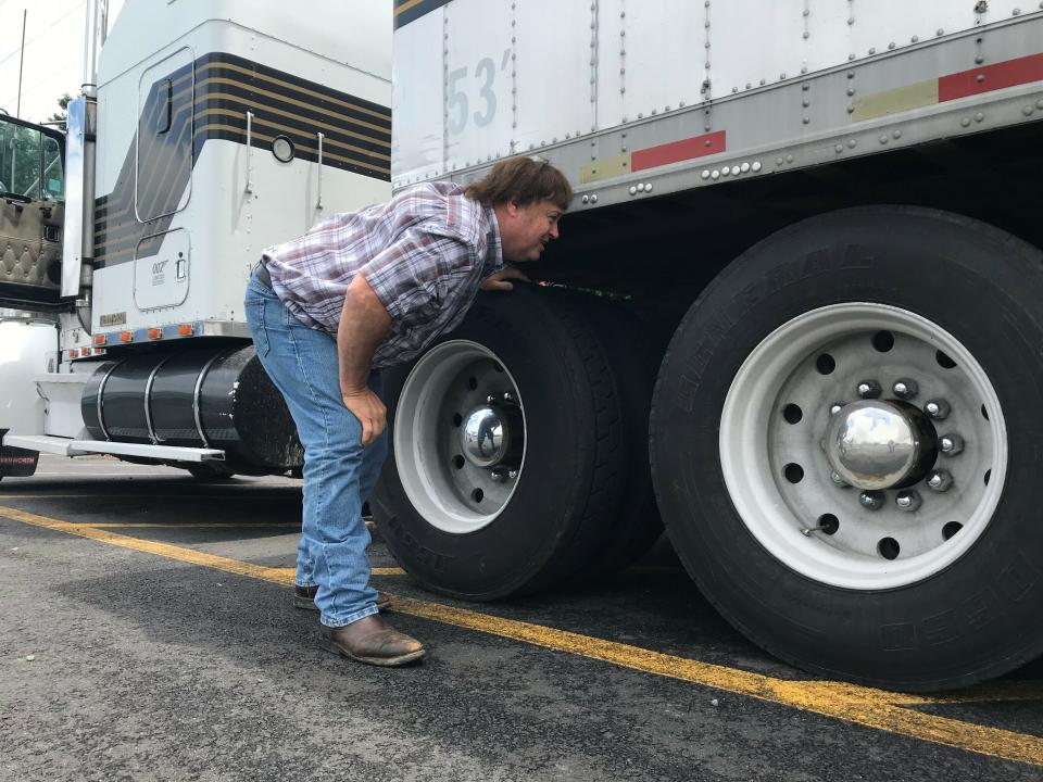 In this June 13, 2019 photo, truck driver Terry Button looks over his trailer during at stop in Opal, Va. The Trump administration has moved a step closer to relaxing federal regulations governing the amount of time truck drivers can spend behind the wheel. (AP Photo/Tom Sampson)