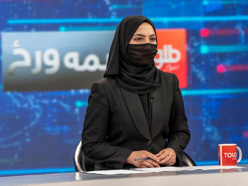 An Afghan woman news reporter covers her face in a live broadcast.