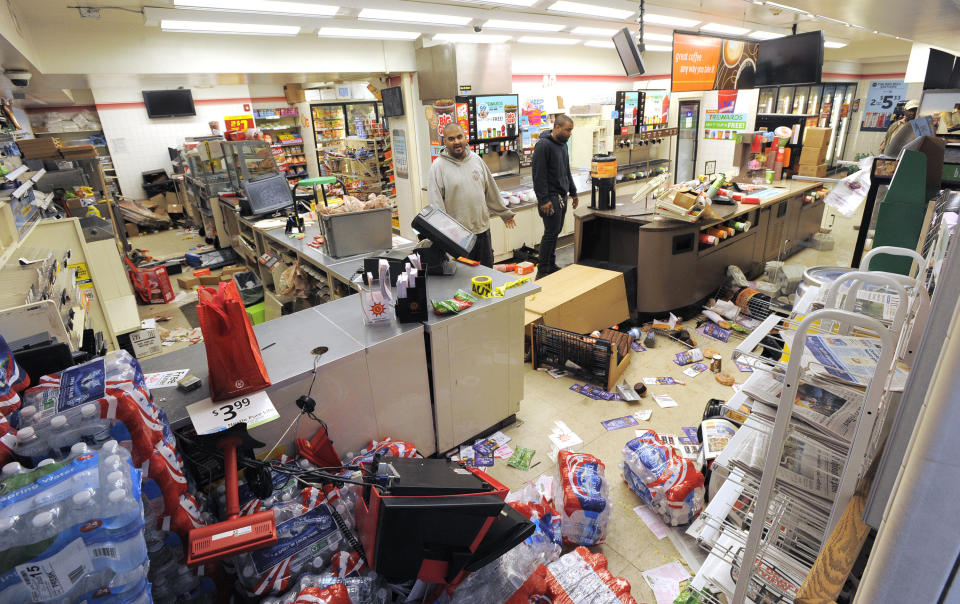 Sam Wirtz, left, an employee of the store, surveys the damage Monday, April 27, 2015, during unrest following the funeral of Freddie Gray in Baltimore. (Lloyd Fox/The Baltimore Sun via AP)