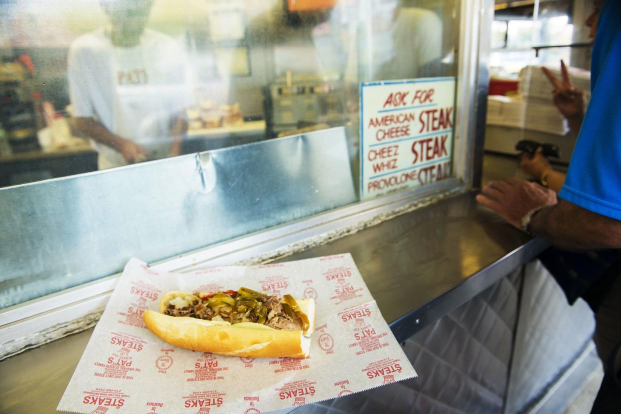 Philadelphia, United States - August 15, 2013: At Pat's King of Steaks, a Philly cheese steak sandwich sits on the outdoor counter top. In the background a couple places an order.