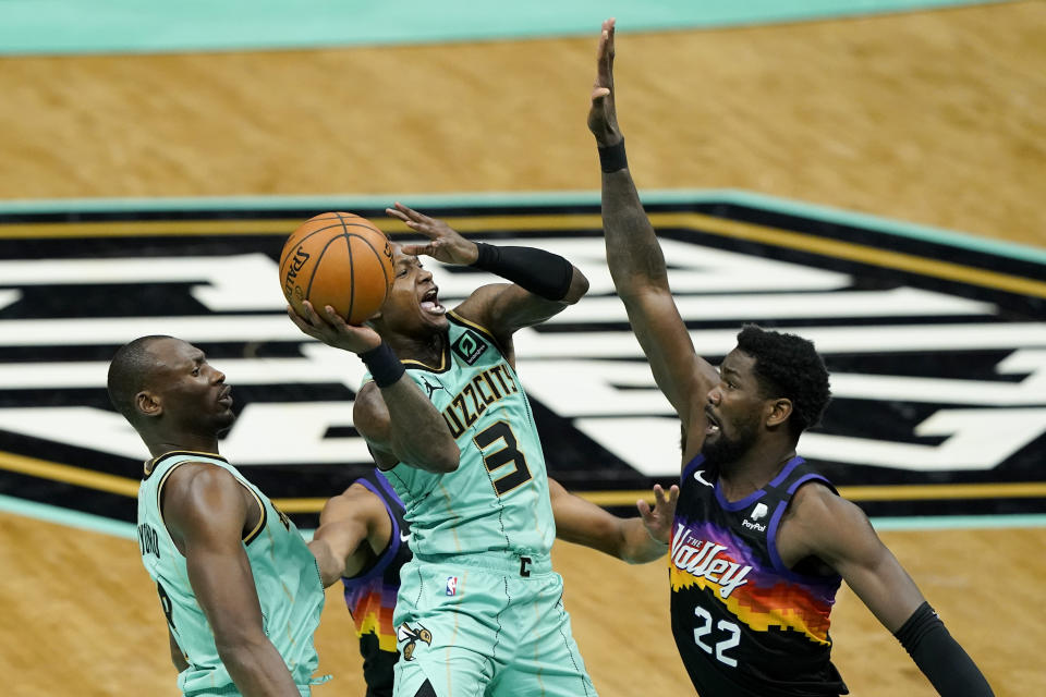 Charlotte Hornets guard Terry Rozier shoots over Phoenix Suns center Deandre Ayton and center Bismack Biyombo looks on during the first half of an NBA basketball game on Sunday, March 28, 2021, in Charlotte, N.C. (AP Photo/Chris Carlson)