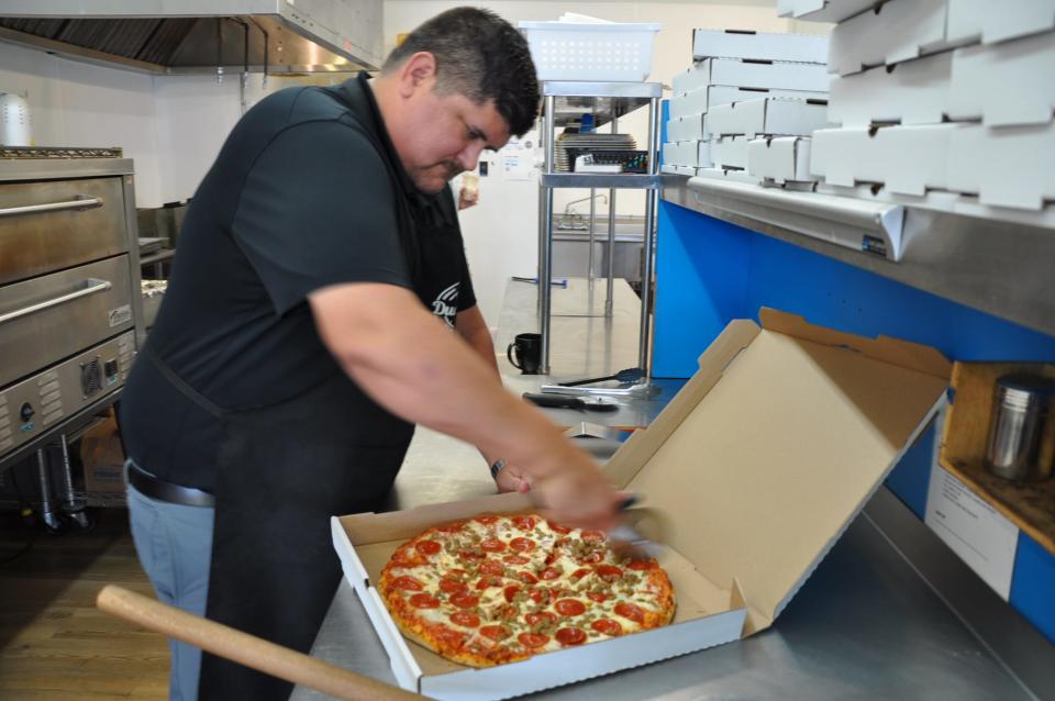 Brian Dudley, co-owner of Dudley's G's Pizza World in Damascus, cuts slices into a large pepperoni and sausage pizza.