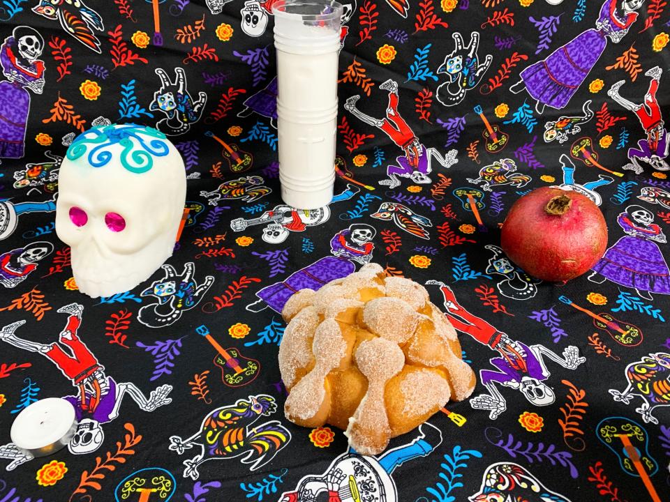 A small pan de muerto sits on an altar along with a sugar skull and a pomegranate at El Kiosco.