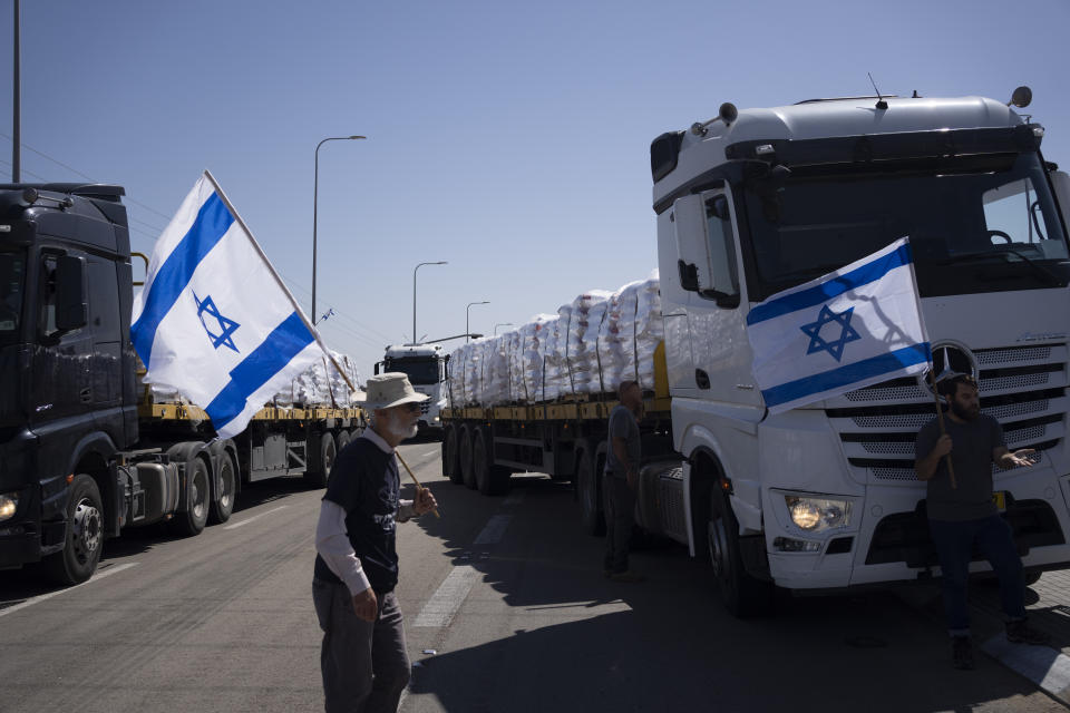 Holding Israeli flags people stand in front of trucks carrying humanitarian aid as they try to stop them to enter in the Gaza Strip in an area near the Kerem Shalom border crossing between Israel and Gaza, in southern Israel, in Kerem Shalom, Thursday, May 9, 2024. (AP Photo/Leo Correa)