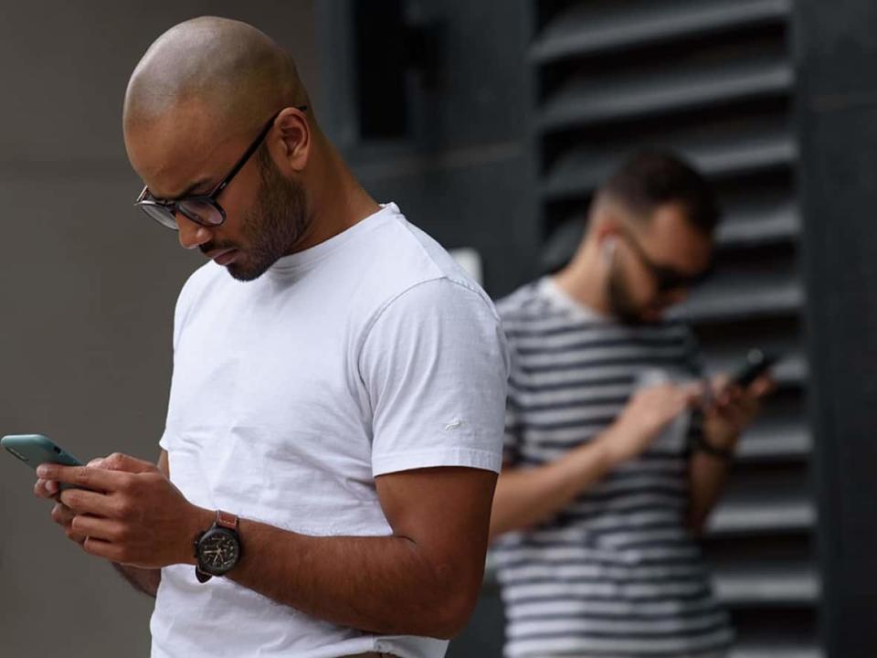 Cellphone users in Toronto fiddle with their phones in the middle of the massive Rogers network outage on Friday. (Alex Lupul/CBC - image credit)