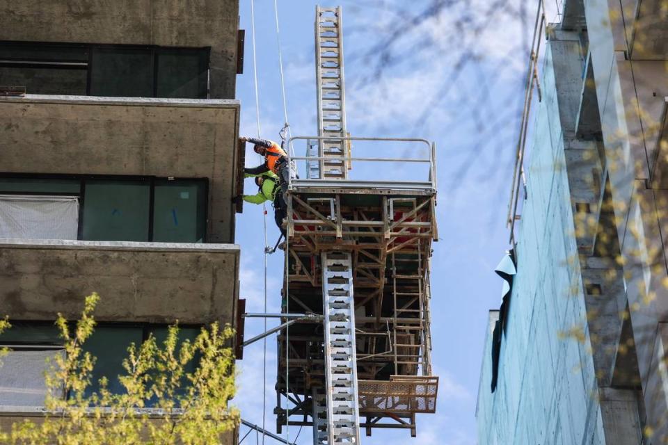 A worker wears the appropriate fall protection while working several floors above the ground at a construction site at East Morehead Street and Euclid Avenue on Wednesday, March 8, 2023
