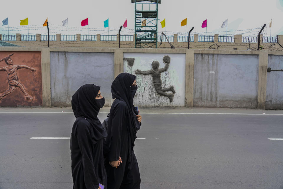 Muslim students walk outside wall of a newly renovated sports stadium ahead of G20 tourism working group meeting in Srinagar, Indian controlled Kashmir, Tuesday, May 16, 2023. Indian authorities have stepped up security and deployed elite commandos to prevent rebel attacks during the meeting of officials from the Group of 20 industrialized and developing nations in the disputed region next week. (AP Photo/Mukhtar Khan)