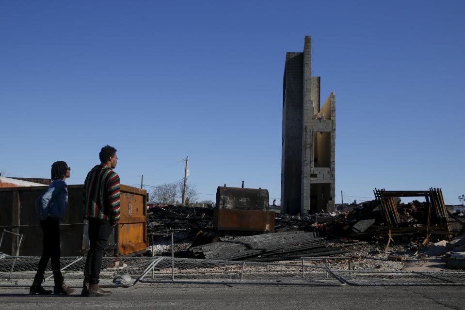 People stand outside the burned community center and apartments across the street from the Southern Baptist Church in Baltimore, Maryland