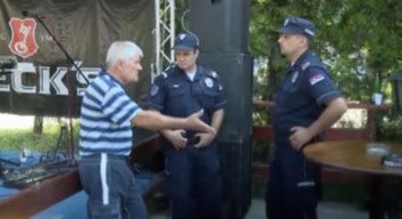 A man talks to police officers at a cafe after a shooting during a local festival in the village of Zitiste, north of Belgrade, Serbia in this still image from video taken July 2, 2016. Courtesy of N1 via REUTERS TV