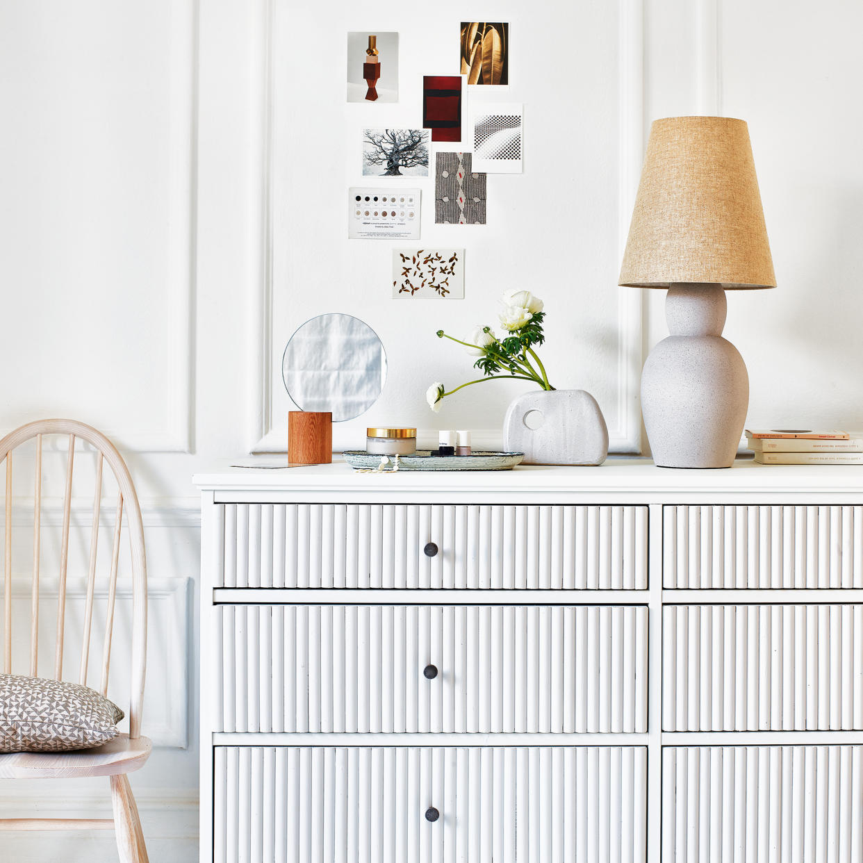  White chest of drawers with mirror, table lamp and artwork 