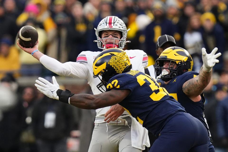Ohio State quarterback Kyle McCord is hit by Michigan defensive end Jaylen Harrell as he throws an interception.