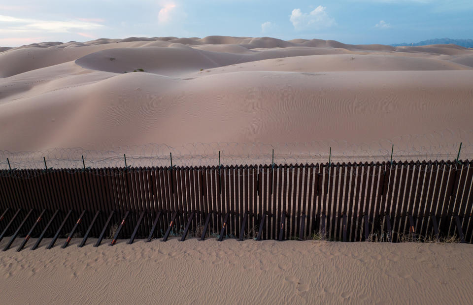 The US–Mexico border fence stands atop sand dunes on Sept. 28, 2022, at Imperial Sand Dunes in California.