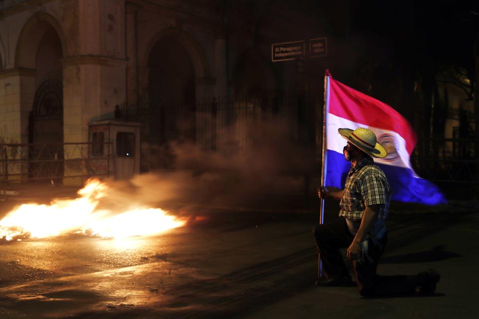 A man carries a national flag during a protest in front of the Congress building, asking for the resignation of President Mario Abdo Benitez over his handling of the coronavirus pandemic and the state of the public health system, in Asuncion, Paraguay, Monday, April 5, 2021. (AP Photo/Jorge Saenz)