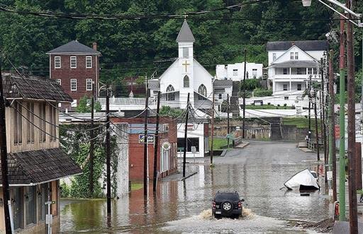 A vehicle makes a wake along the flooded Lower Oakford Ave. Friday, June 24, 2016, in Richwood, W.Va. (Rick Barbero/The Register-Herald)